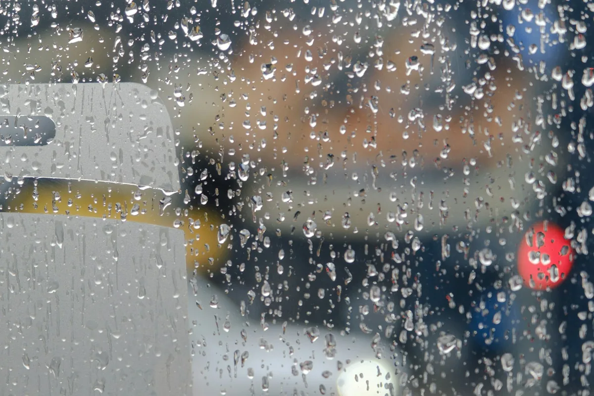 雨粒のついた窓ガラス。外の景色はぼやけている