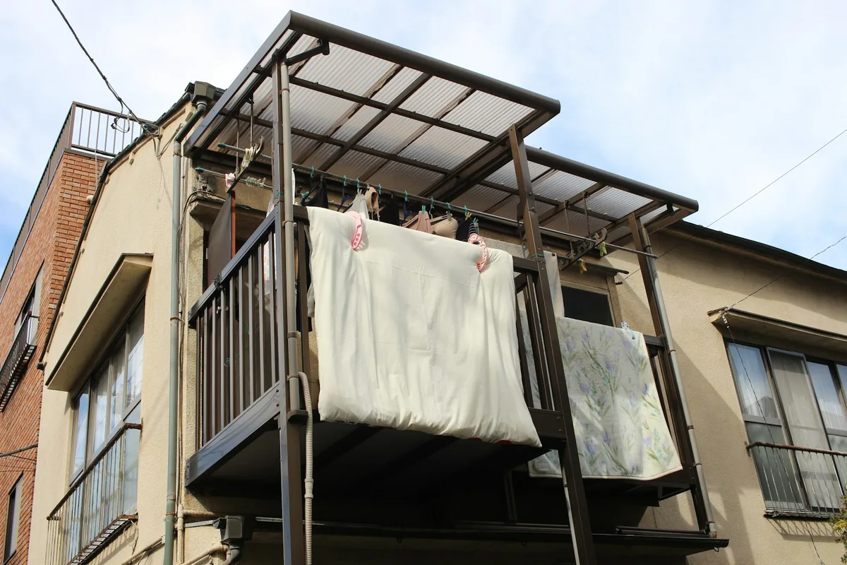 集合住宅のベランダに干された布団と毛布