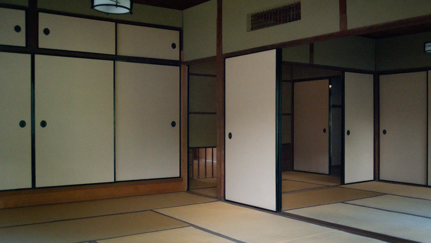 誰もいない和室。畳の上に襖が並び、一枚だけ開いている