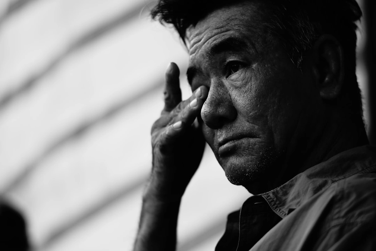 こめかみのあたりに手を当てている高齢の男性