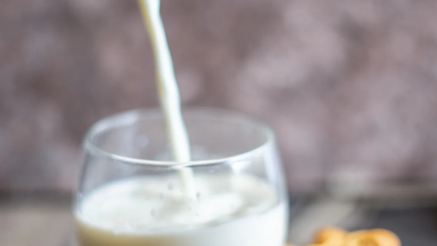 ガラスのコップに牛乳が注がれているところ