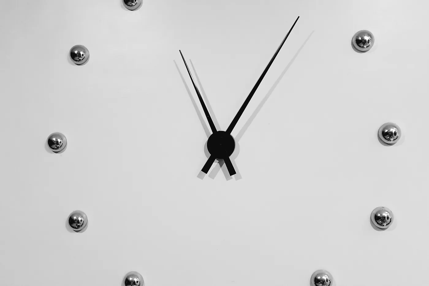 白い壁にかかる、数字のない壁掛け時計