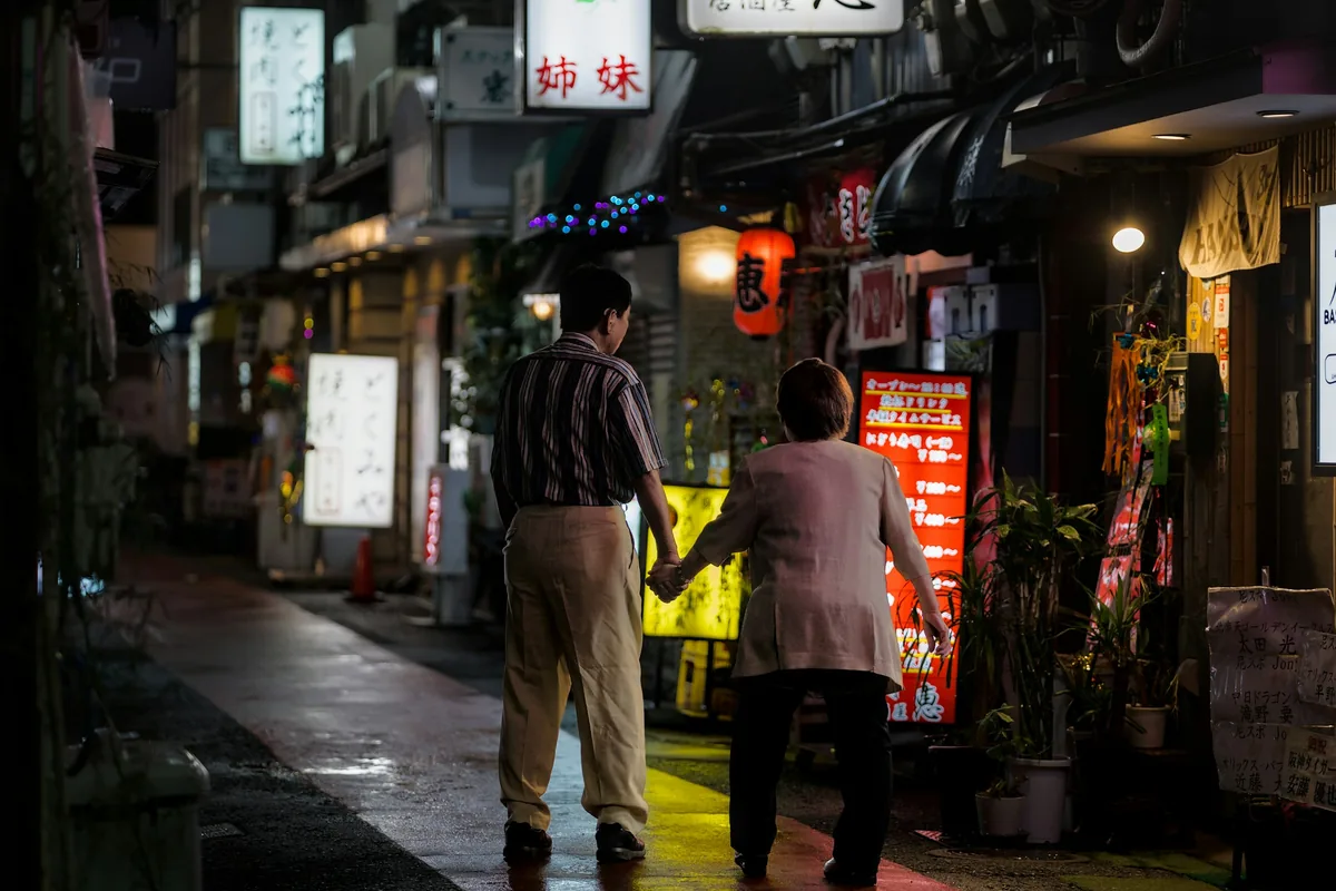 年配のご夫婦が、腕を組んで通りを歩いている後ろ姿