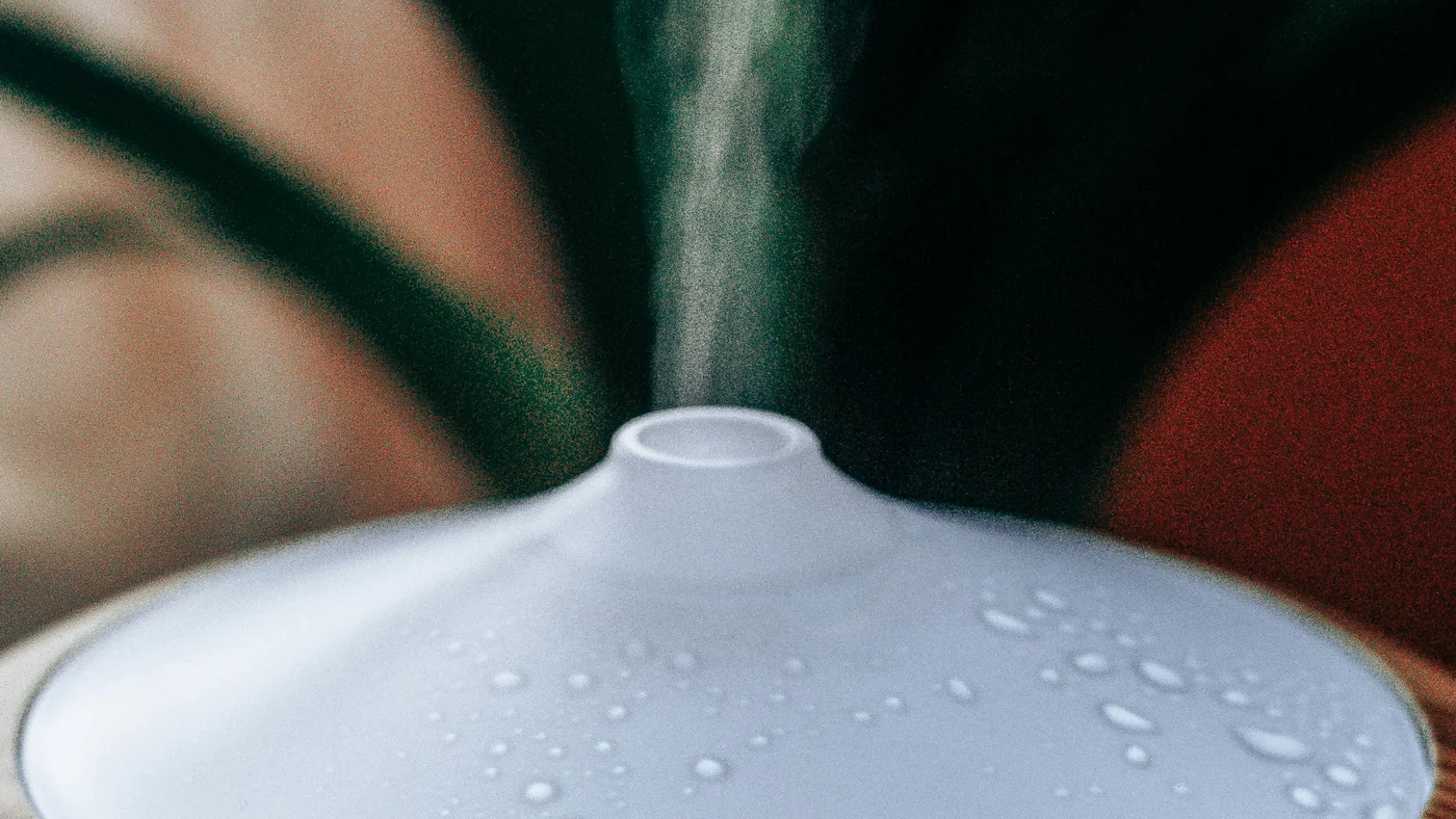 加湿器の白い吹き出し口から細いミストが立ちのぼり、本体の表面に水滴がついている