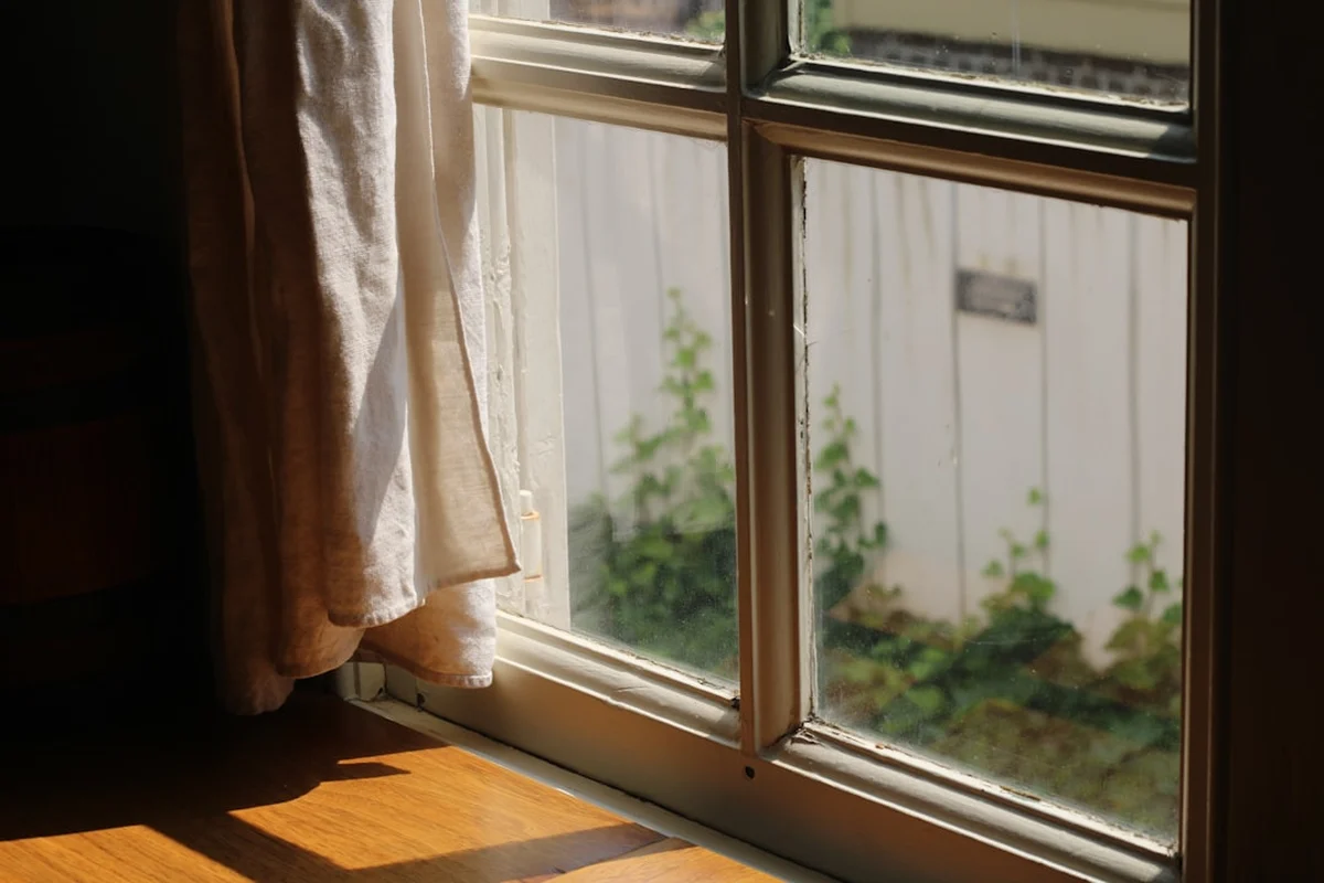 朝の光が差し込む、木枠の窓と木の床