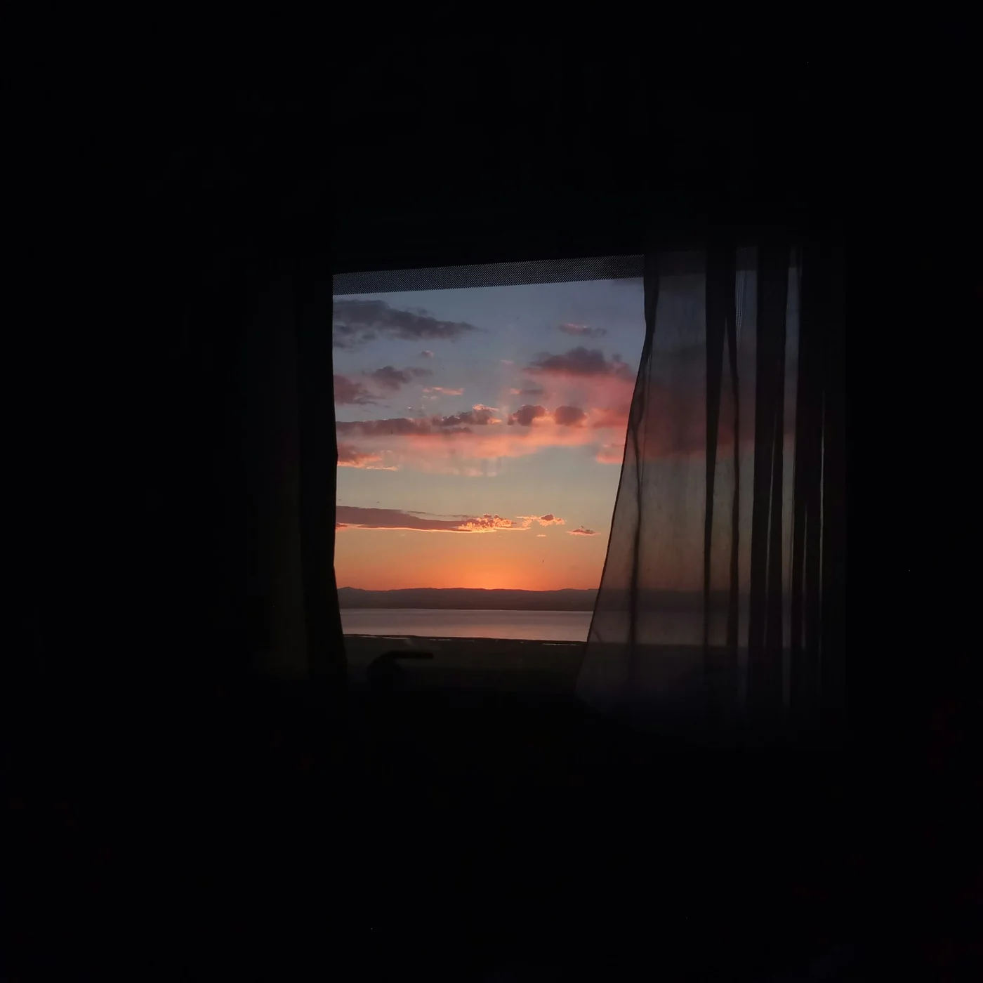 暗い部屋の窓と、夕焼け