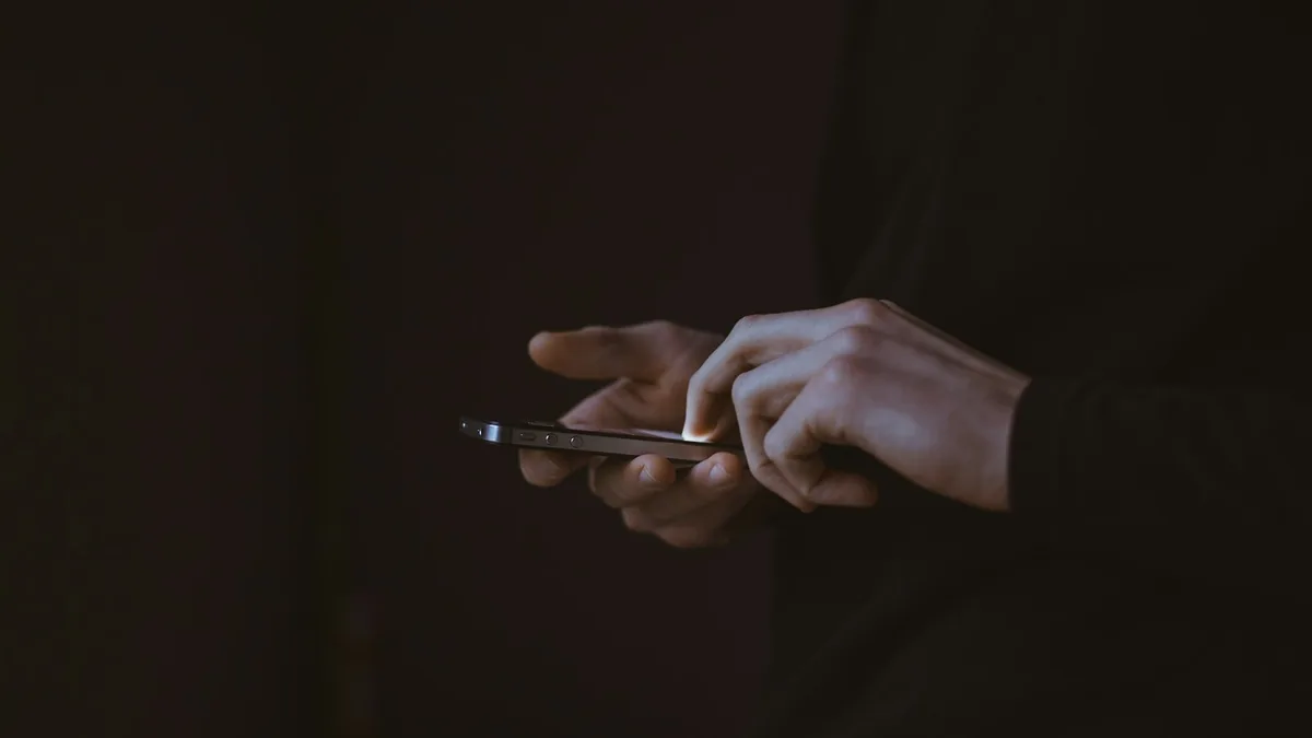暗がりでスマートフォンを操作する手