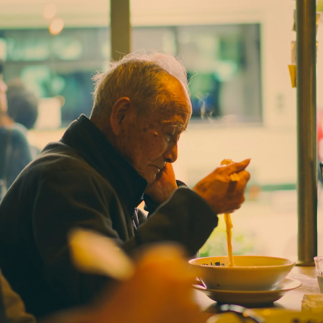 高齢の男性がひとりで食事をしている