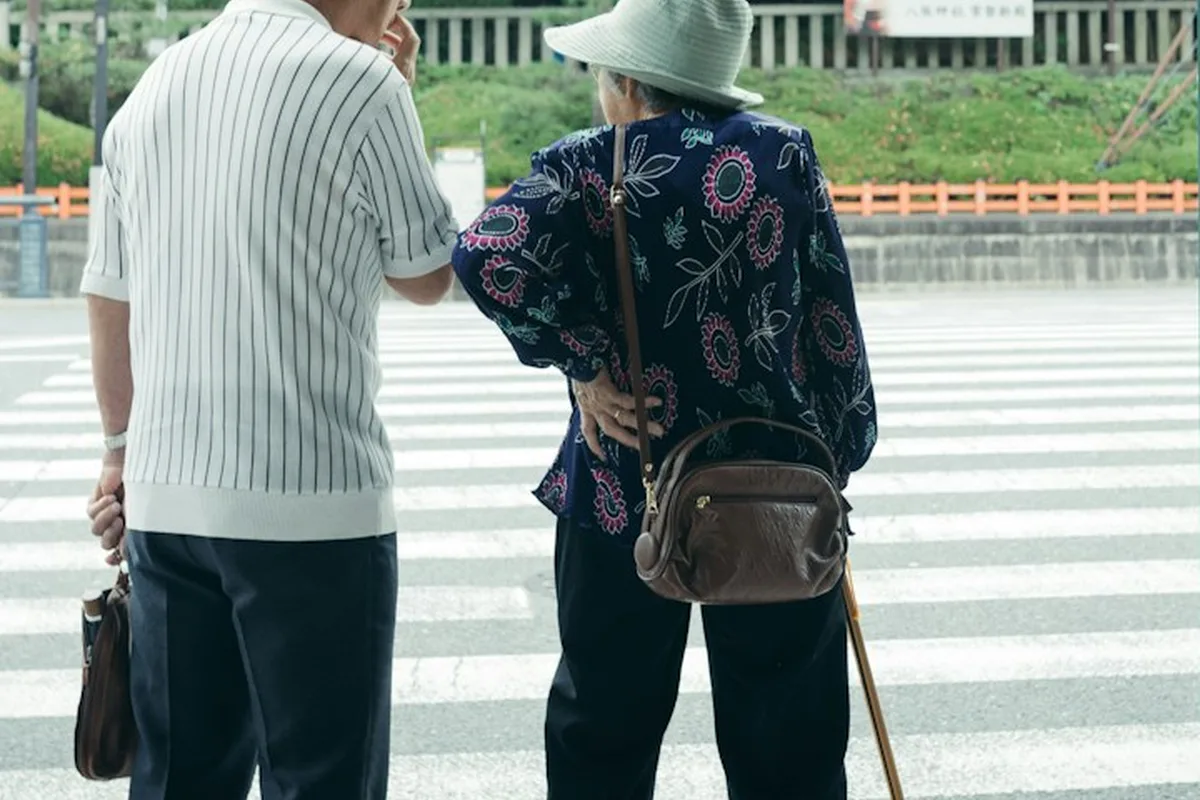 横断歩道の前に並んで立つ高齢のご夫婦の後ろ姿