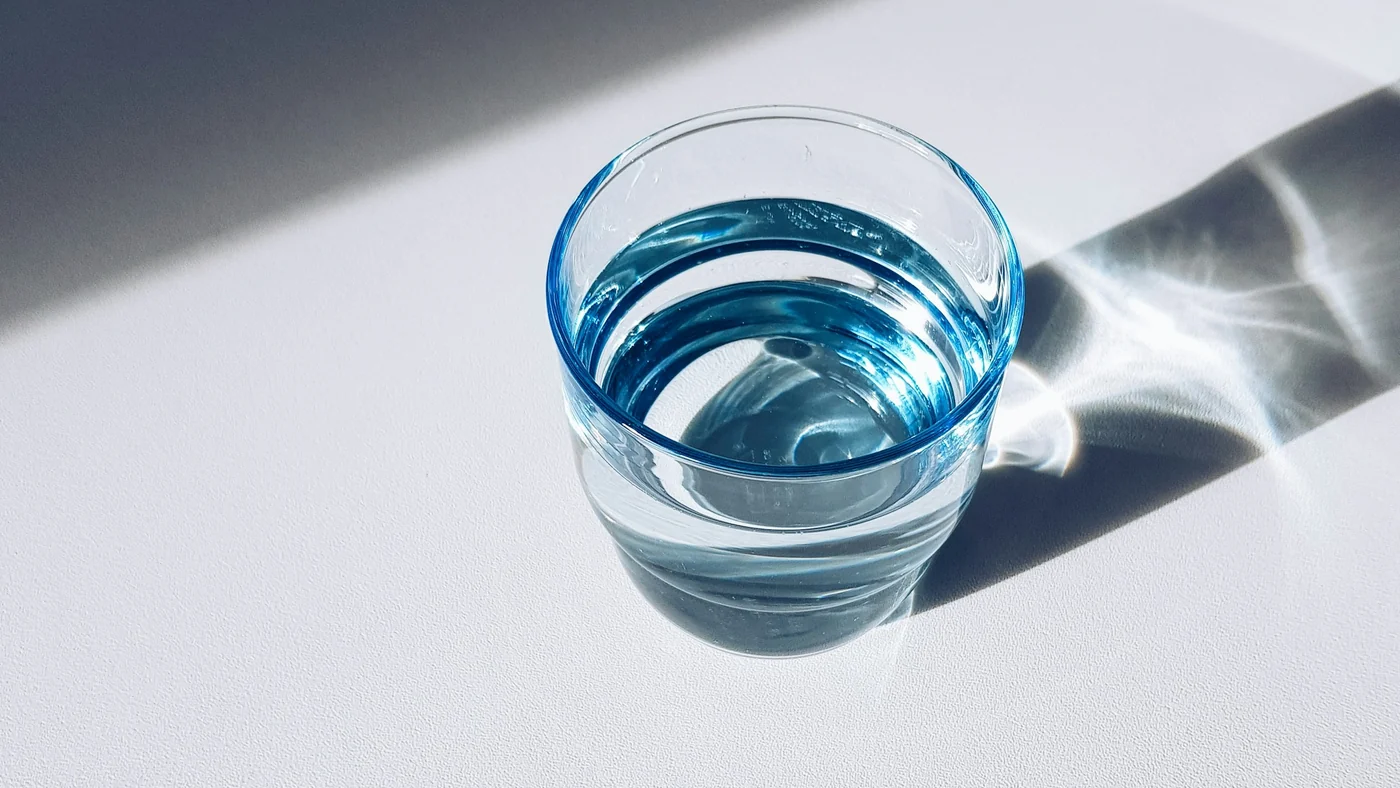 白い机に置かれた、水の入ったガラスのコップ