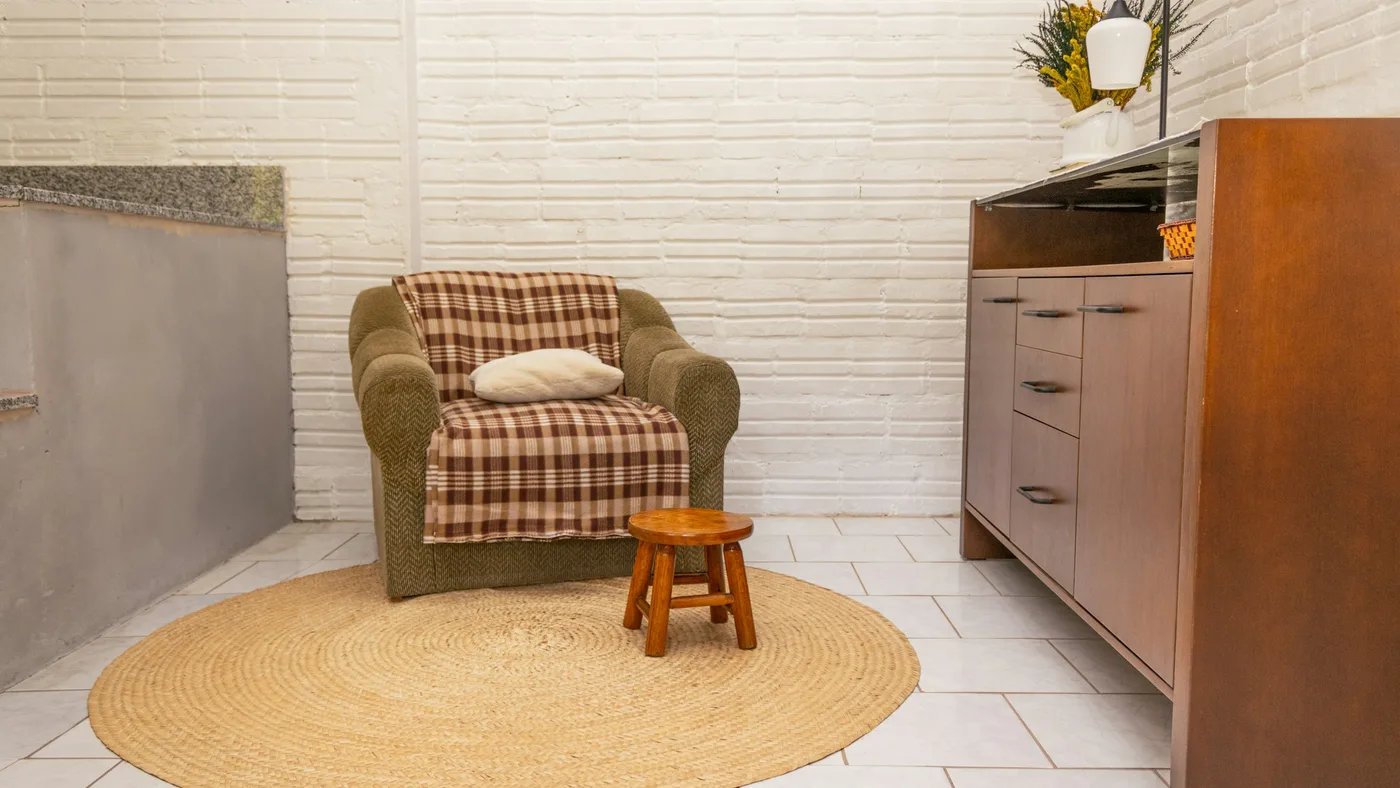 白い壁の部屋に置かれた一人掛けのソファと丸い敷物