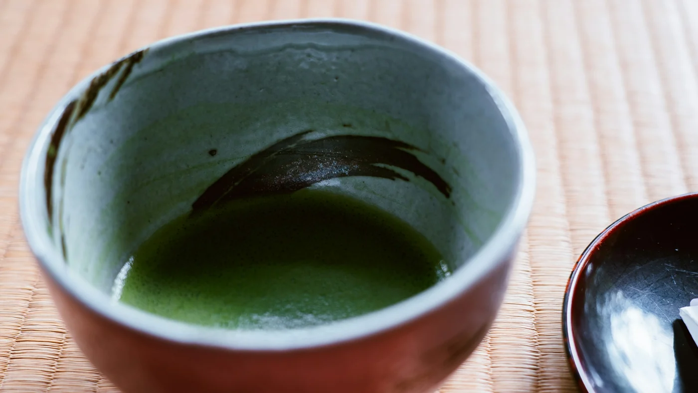 畳の上に置かれた茶碗を真上から見たところ。薄く点てた緑の茶が入っている