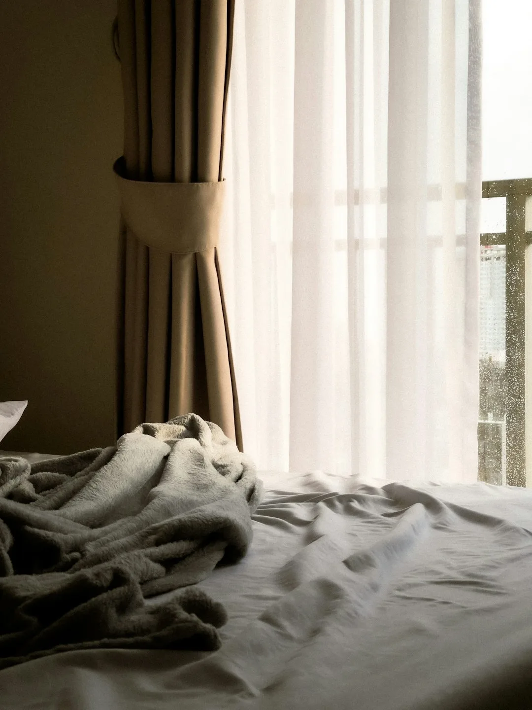 レースのカーテン越しに光が入る寝室