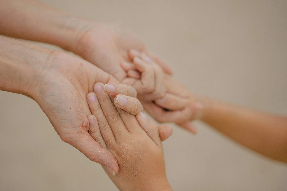 大人の手が子どもの手を包むように握っている