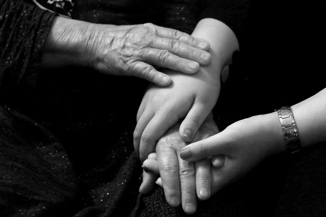 年配の手に、若い手が重ねられている