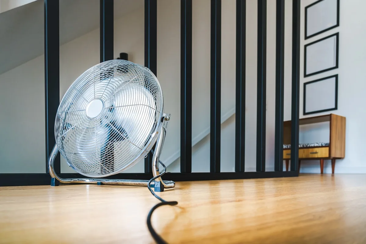 フローリングの部屋に置かれた扇風機。電源コードが床にのびている
