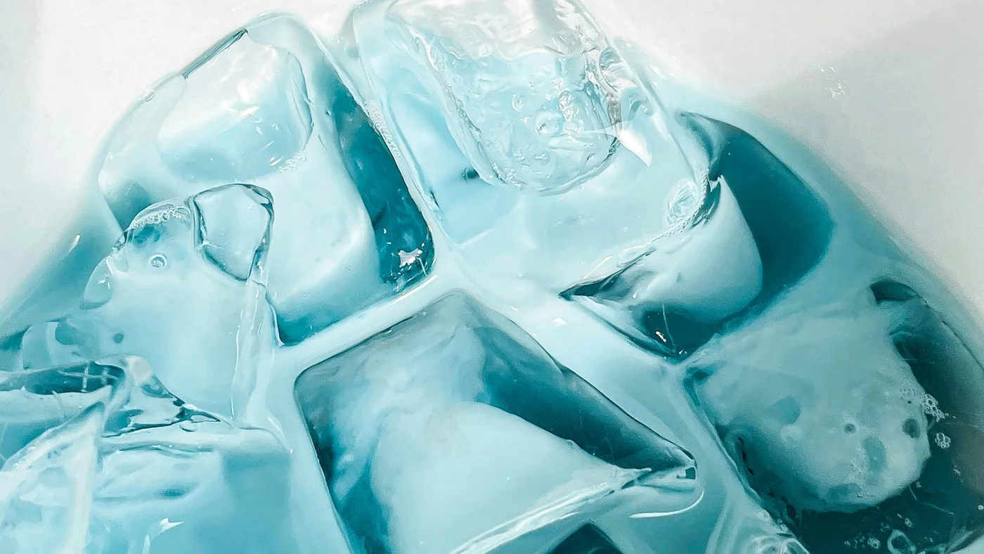 白い器に張った水の中に、四角い氷がいくつも沈んでいる様子を真上から見たところ