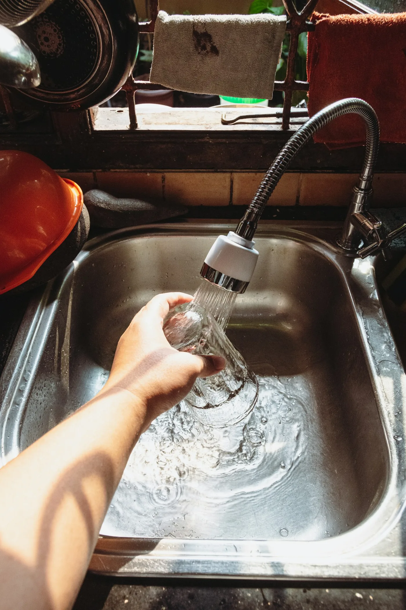 台所のシンクで、蛇口の水をコップに注いでいる手元