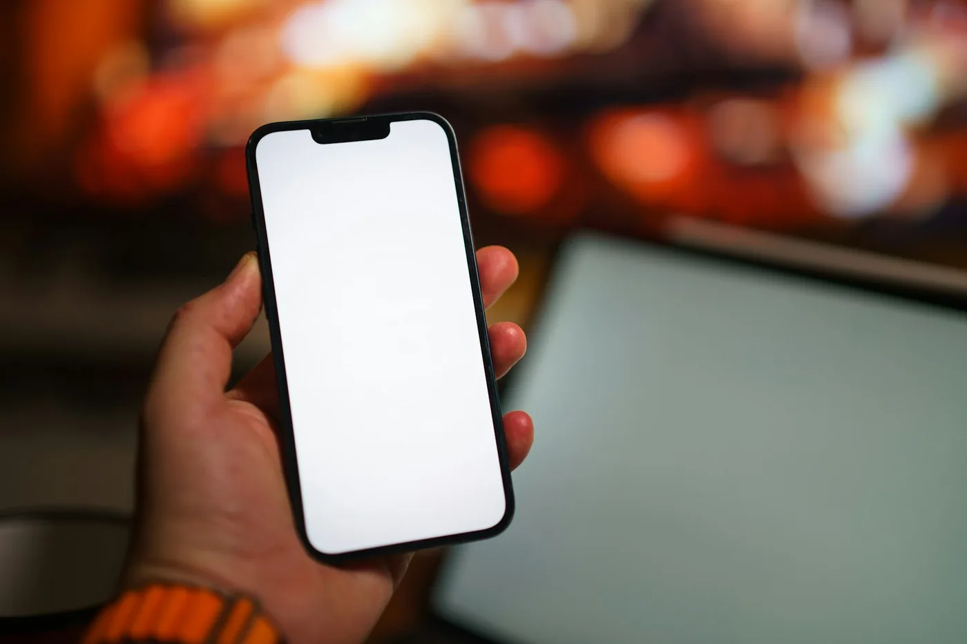 夜、スマートフォンを片手に持っている手元。画面は白く光っている